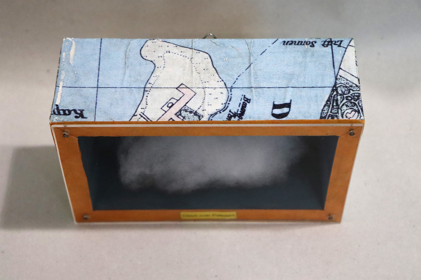 Original Objekt - Assemblage von Elisabeth Dishur, Titel „Clouds over Potsdam"– Objektkiste. Draufsicht auf Stadtkarte auf der Holzkiste: Papiercollage mit Stadtkarte von Potsdam umfassend auf der Kiste. Objektcollage, erhältlich bei Galerie Waldbach - What The Artist Made