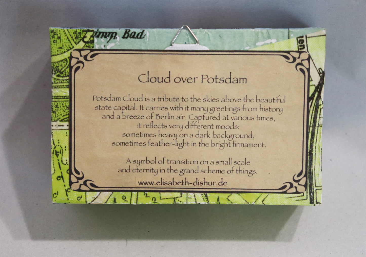 Original Objekt - Assemblage von Elisabeth Dishur, Titel „Clouds over Potsdam" – Objektkiste. Rückansicht, Beschreibung: Potsdam cloud is a tribute to the skies above the beautiful state capital (Auszug) Papiercollage mit Stadtkarte von Potsdam umfassend auf der Kiste. Aufhänger. Objektcollage, erhältlich bei Galerie Waldbach - What The Artist Made