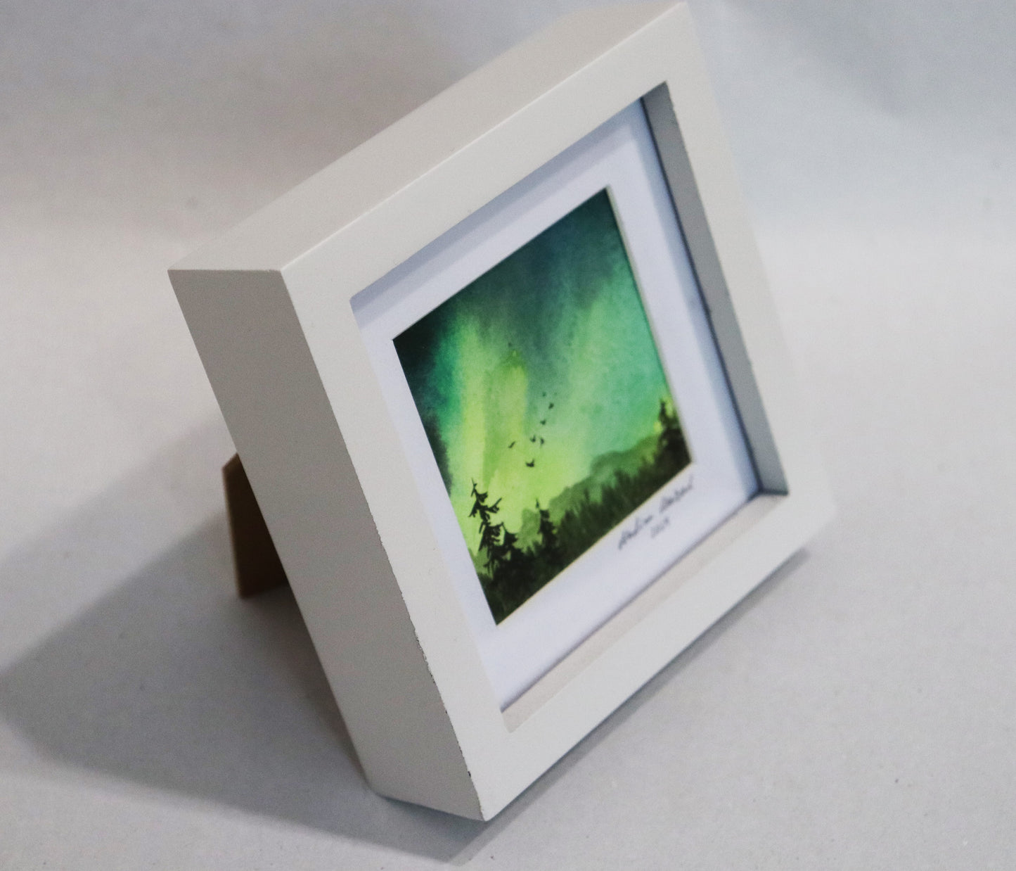 Original Aquarell-Malerei, Gemälde von Nadine Conrad, Titel „Landschaften“ – Landschaft mit Wetterleuchten/Polarlichtern in grün, Tannenwald und Vogelschwarm, Aquarell auf Papier, erhältlich bei Galerie Waldbach - What The Artist Made