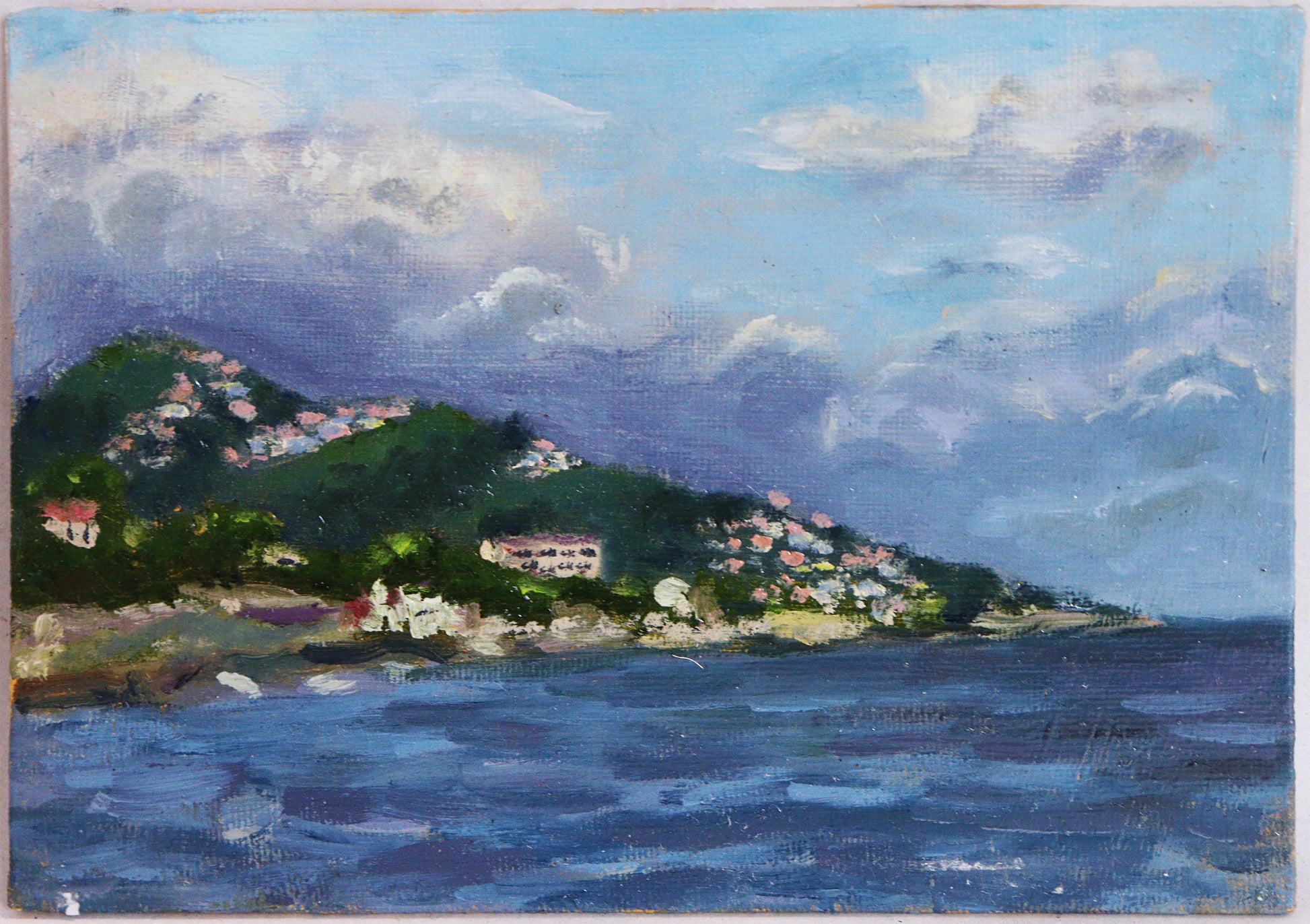 Original Öl-Malerei, Gemälde von Anastasia Wiggert, Titel „Küste“ – impressionistischer Blick auf eine Küstenszene mit Berg im Hintergrund, auf dem vereinzelte Dörfer erkennbar sind. Häuser im Mittelgrund entlang der Küstenlinie erkennbar. Blau als farblicher Schwerpunkt, Meer im Vordergrund. Öl auf Platte, erhältlich bei Galerie Waldbach - What The Artist Made