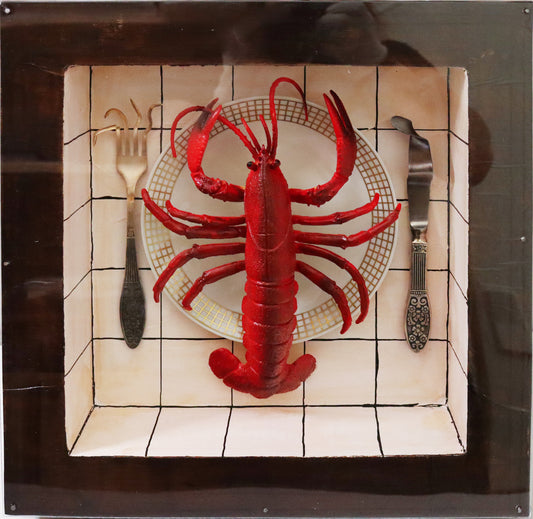 Original Objekt - Assemblage von Elisabeth Dishur, Titel „Hummer“ – Objektkiste mit Gegenständen: Ein roter Hummer aus Kunststoff liegt auf einem weißen Teller mit Goldrand, links und rechts liegen Gabel und Messer, die Zinken und Schneide verbogen. Der Hintergrund ist weiß mit schwarzen Quadraten -  an Fließen erinnernd. Eingefasst in eine Holzkiste, mit Plexiglas versehen - Objektcollage, erhältlich bei Galerie Waldbach - What The Artist Made