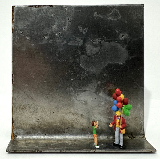 Original Objekt - Assemblage von Katrin Schramm, Titel „Lass sie fliegen…“ – Metallwinkel mit Miniatur-Figuren: Ballonverkäufer auf dem Winkel stehend, daneben ein Kind, welches auf die Luftballons zeigt, die er in der Hand festhält. Dahinter das Metall des Winkels als Hintergrund. - Objektcollage, erhältlich bei What The Artist Made