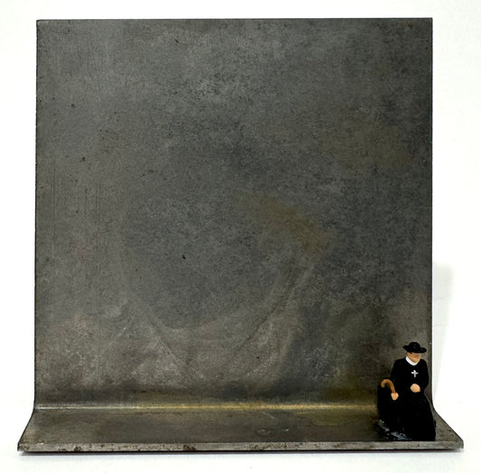 Original Objekt - Assemblage von Katrin Schramm, Titel „Sonderzug“ – Metallwinkel mit Miniatur-Figur: ein Priester/Pfarrer, am rechten Rand des Metallwinkels sitzend. Dahinter das Metall des Winkels als Hintergrund. - Objektcollage, erhältlich bei What The Artist Made