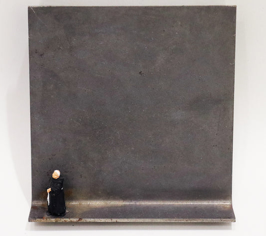 Original Objekt - Assemblage von Katrin Schramm, Titel „Wenn ich stehe, dann stehe ich.“ – Metallwinkel mit Miniatur-Figur: am linken Bildrand Mönch in schwarzem Habit stehend, mit gefalteten Händen und zur Seite schauend. Dahinter das Metall des Winkels mit Struktur, als Hintergrund. - Objektcollage, erhältlich bei Galerie Waldbach - What The Artist Made