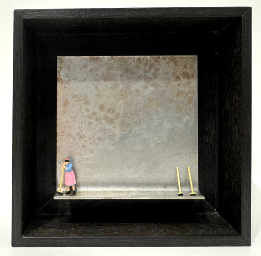 Original Objekt - Assemblage von Katrin Schramm, Titel „das bißchen Haushalt…“ – Metallwinkel mit Miniatur-Figur: Frau links am Rand des Winkels stehend, stützt sich auf Besen. Rechts am Rand zwei weitere Besen gegen den Hintergrund des Metallwinkels gelehnt. - Objektcollage, erhältlich bei What The Artist Made