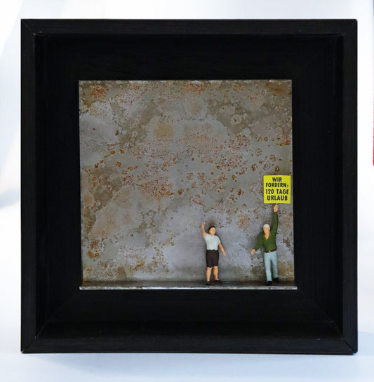 Original Objekt - Assemblage von Katrin Schramm, Titel „sind dann mal weg...“ – Metallwinkel mit Miniatur-Figuren: Zwei Personen stehen rechts auf dem Winkel. Die linke Person streckt einen Arm mit Faust hoch, die andere trägt ein gelbes Schild - Anmutung einer Demonstration. Auf dem Schild steht: "Wir fordern: 120 Tage Urlaub". Dahinter das Metall des Winkels mit Struktur, als Hintergrund. In einem schwarzen Rahmen aus Holz. Objektcollage, erhältlich bei Galerie Waldbach - What The Artist Made
