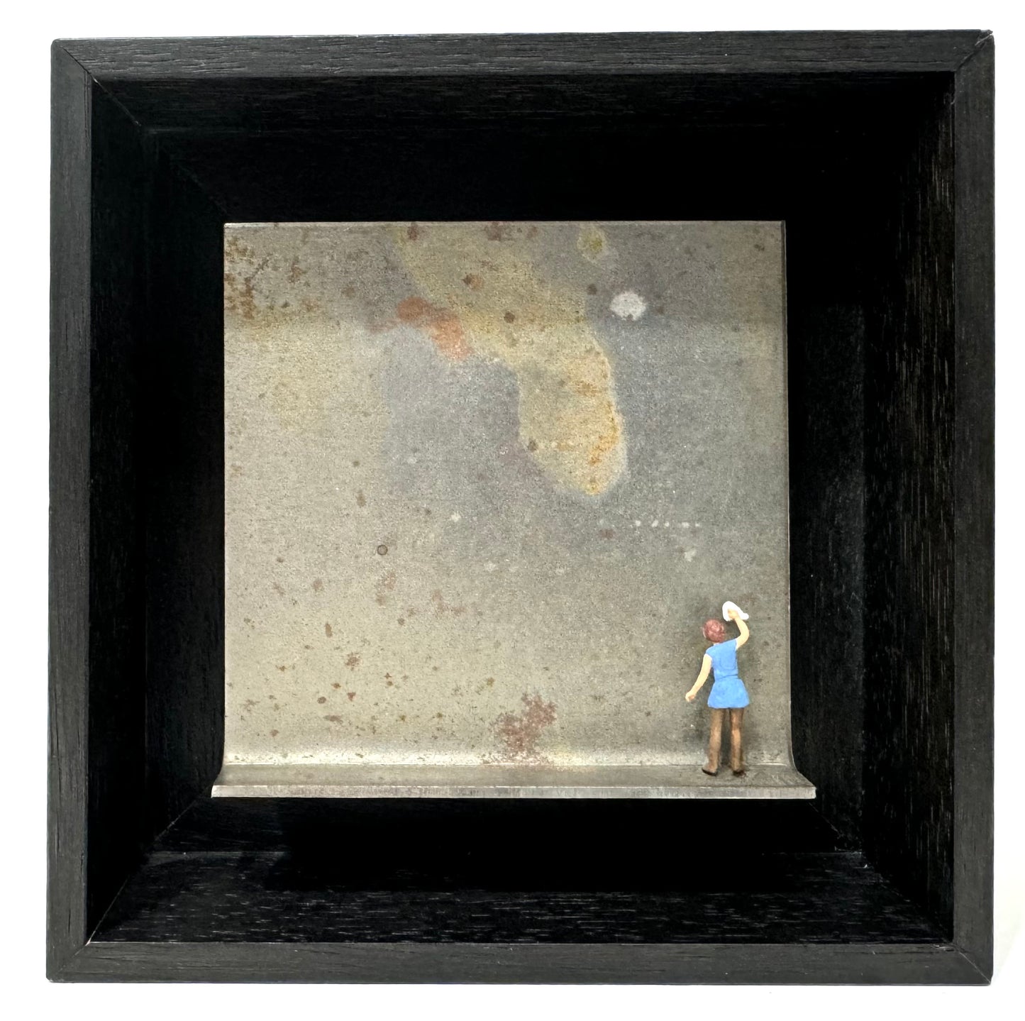 Original Objekt - Assemblage von Katrin Schramm, Titel: „Ich möchte ein Glanz sein“ – Metallwinkel mit Miniatur-Figur: Frau in blauem Kleid auf dem Winkel stehend, Rücken zum Betrachter, den Hintergrund des Metallwinkels putzend. Dahinter das Metall des Winkels als Hintergrund. - Objektcollage, erhältlich bei What The Artist Made