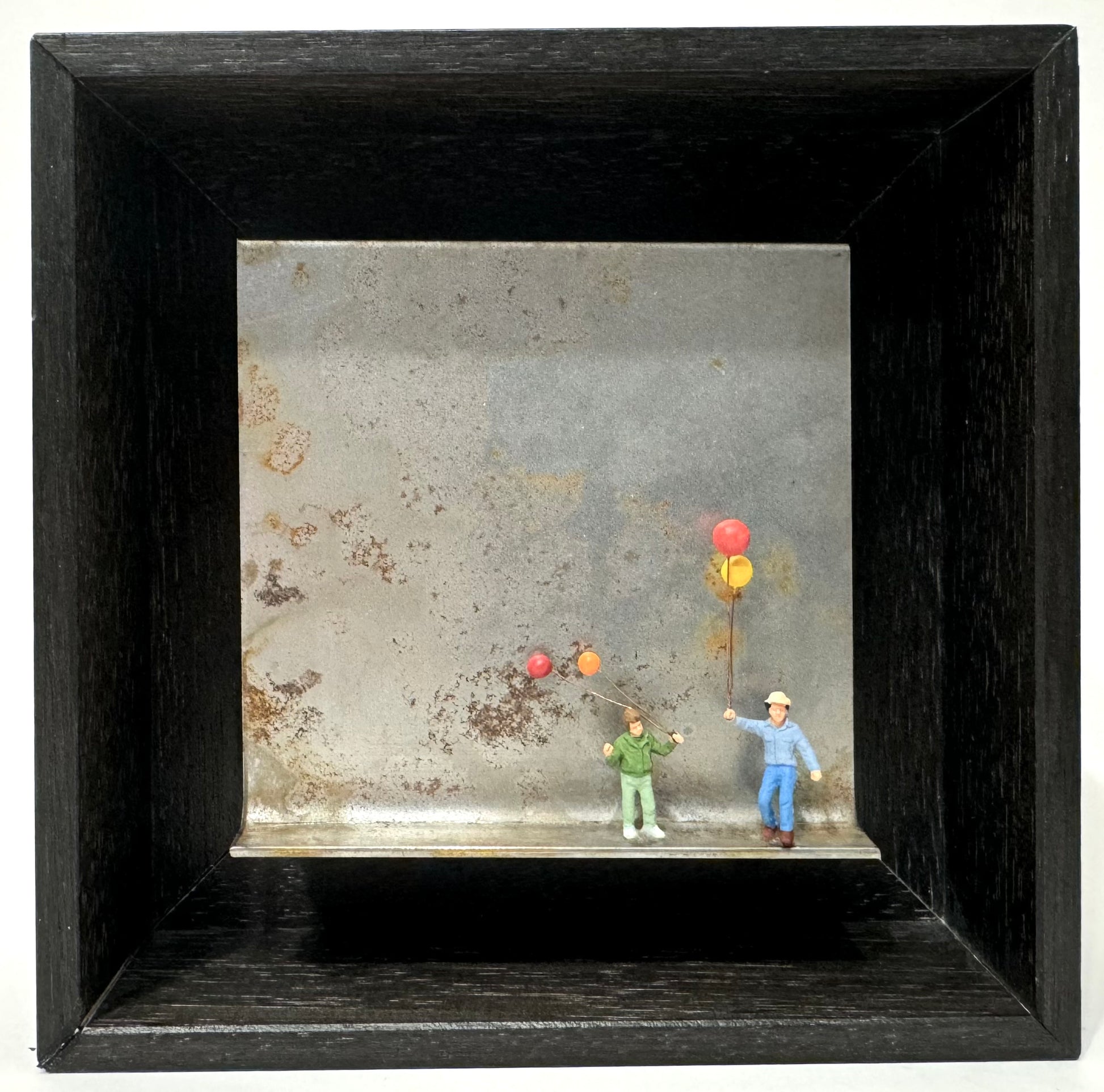 Original Objekt - Assemblage von Katrin Schramm, Titel „Mehr als nur Luft…“ – Metallwinkel mit Miniatur-Figuren: zwei Kinder rechts auf dem Winkel stehend,  beide halten je zwei Ballons in der Hand in rot, gelb , orange. Dahinter das Metall des Winkels als Hintergrund. - Objektcollage, erhältlich bei What The Artist Made