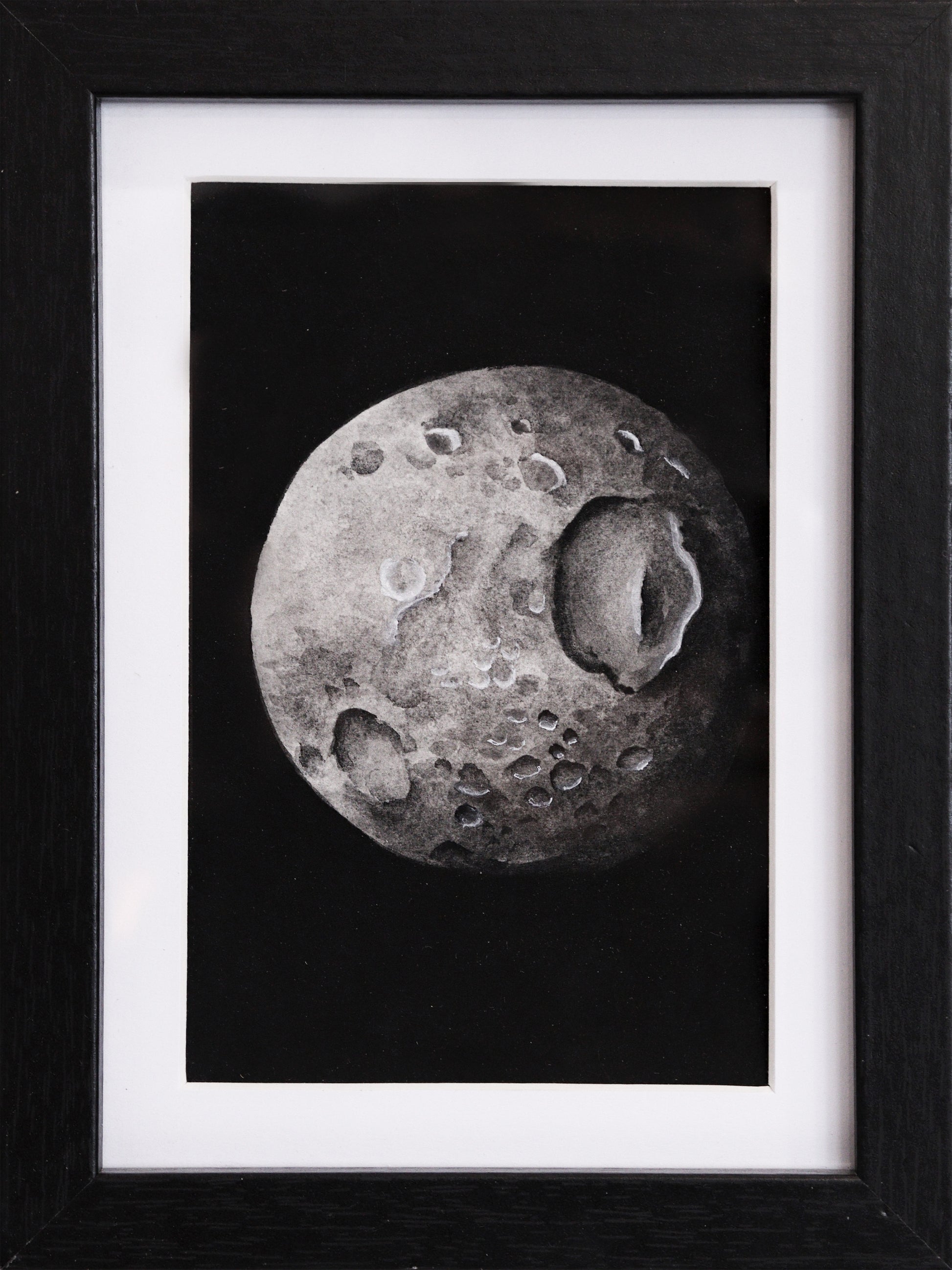Original Aquarell-Malerei, Gemälde von Lisa Steinbrück, Titel „Mimas“ – Darstellung eines der Monde des Saturns in Aquarell-Stil, schwarz-weiß und Grautöne auf schwarzem Grund, Aquarell auf Papier, gerahmt, schwarzer Rahmen mit weißem Passepartout,  erhältlich bei Galerie Waldbach - What The Artist Made