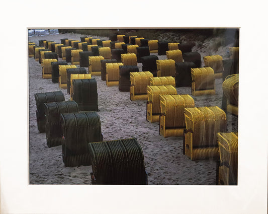 Original Cyanotypie Fotografie, von Uwe Paul Schulze, ohne Titel – Ansicht schwarzen und gelben Strandkörben, vom Betrachter weg ausgerichtet am Strand. Cyanotypie auf Papier, in Schutzhülle, mit weißem Passepartout, erhältlich bei Galerie Waldbach - What The Artist Made